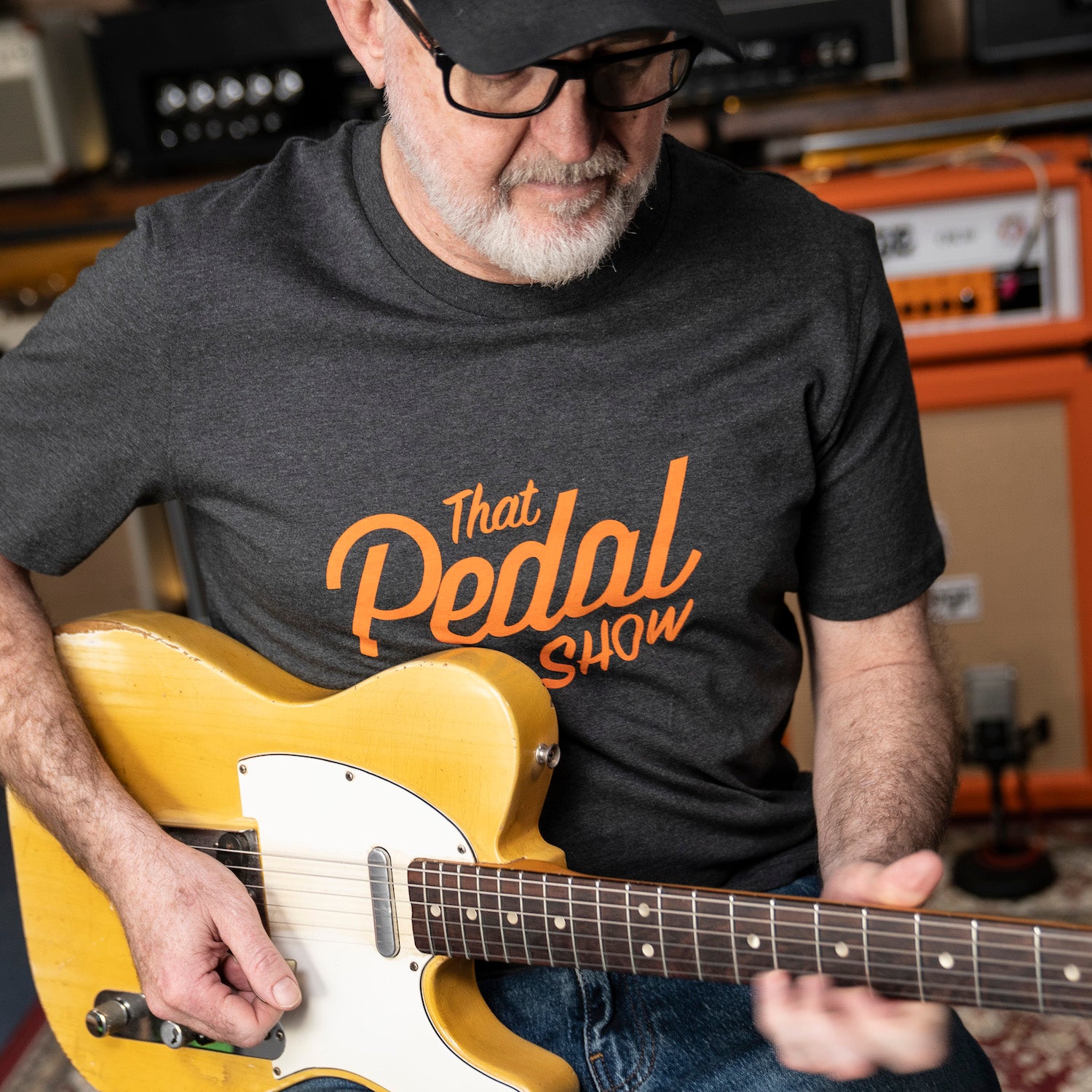 Dan wearing a 'That Pedal Show' vintage logo t-shirt holding a yellow Fender Telecaster guitar in the TPS Studio