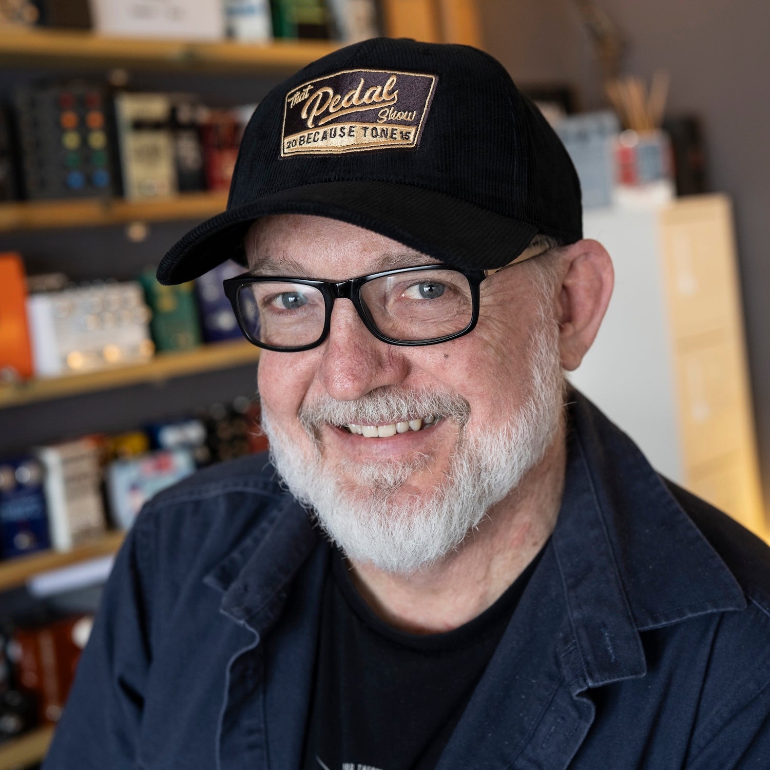 Dan wears black cord baseball cap with vintage That Pedal Show logo embroidered onto front.