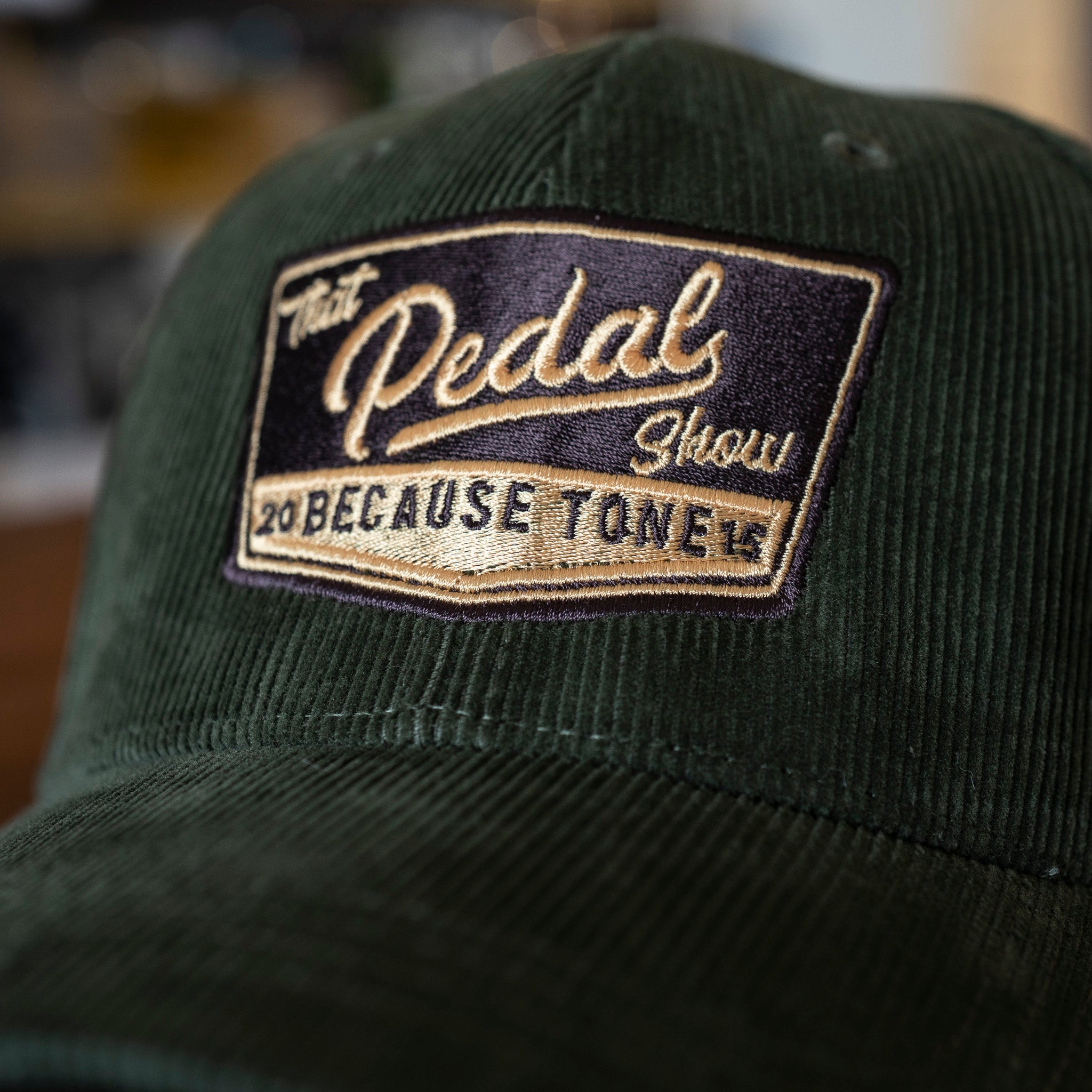 Close up of Forest Green corduroy baseball cap with vintage That Pedal Show logo embroidered onto front.